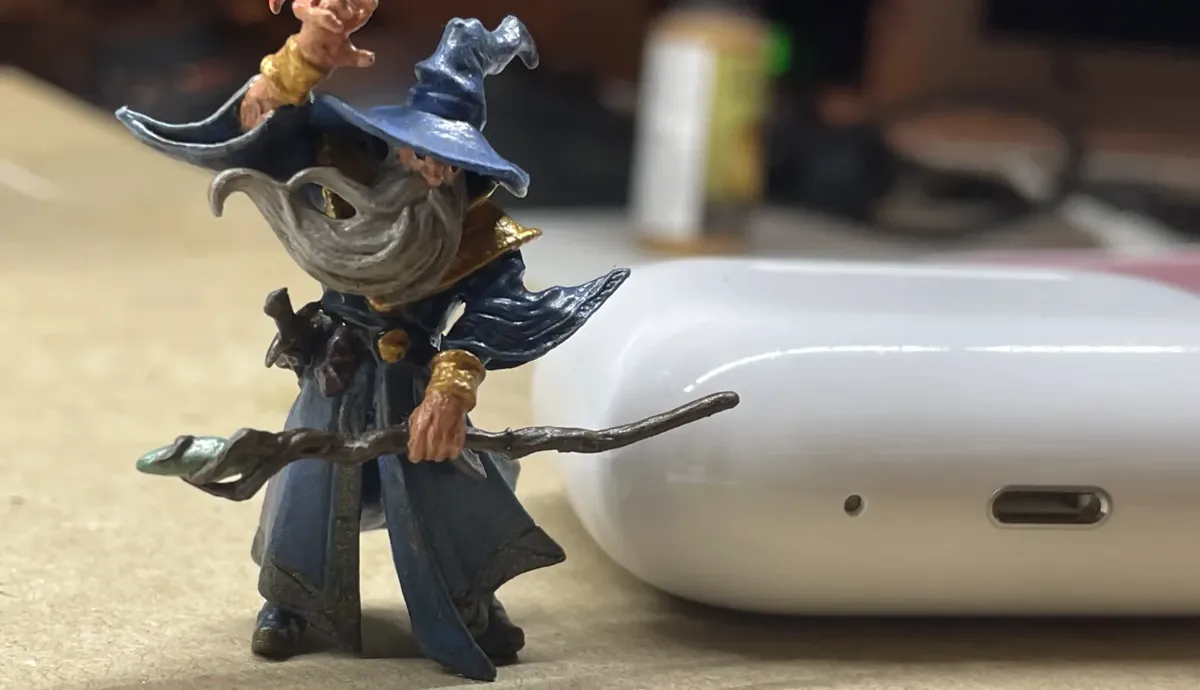 Evoker Wizard miniature beside an Apple AirPods case for scale